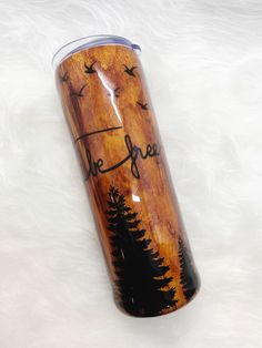 a wooden tumbler with the words the forest on it and birds flying over trees