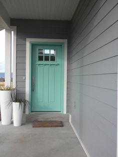 two planters on the front porch of a house with a blue door and window