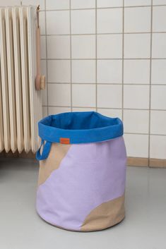 a large purple and blue basket sitting on the floor next to a radiator