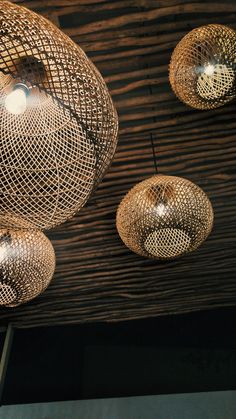 several lights hanging from the ceiling in a room with wood paneling and metal wire