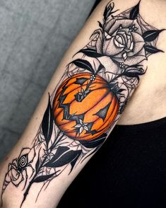 a woman's arm with a pumpkin and roses tattoo on the left side of her arm