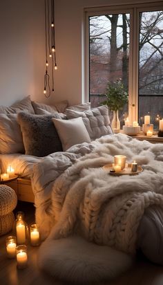 a bed with candles and blankets on it in front of a window filled with windows