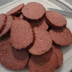 there is a white plate with some sausages on it and a knife next to it