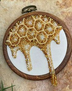 a wooden frame holding a gold beaded tree ornament on a stone surface