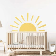 a baby's room with a crib and sun decal on the wall