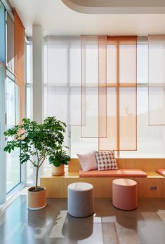 a living room filled with lots of windows next to a potted plant and two stools