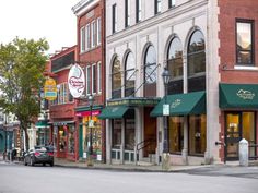 an empty street with stores and cars parked on the side walk in front of it