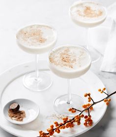 three glasses filled with drinks sitting on top of a white plate