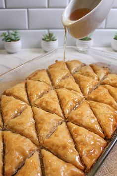 someone pouring syrup on some food in a pan