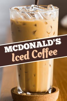 iced coffee in a tall glass sitting on top of a wooden table next to a sign that reads mcdonald's iced coffee