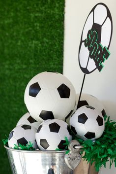 some soccer balls are in a bucket on the table