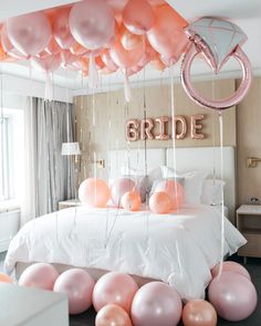 balloons and streamers are hanging from the ceiling above a bed with a bride sign on it