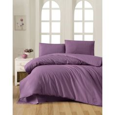 a bed with purple sheets and pillows in a room