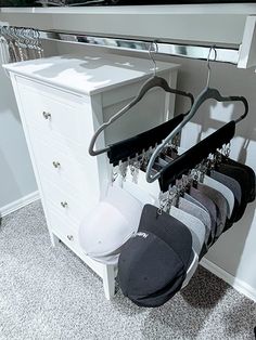 there are several hats hanging on the clothes rack in this closet, and one is empty