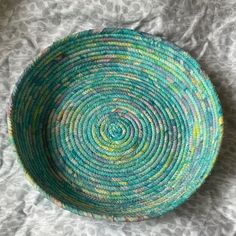 a green and blue bowl sitting on top of a bed