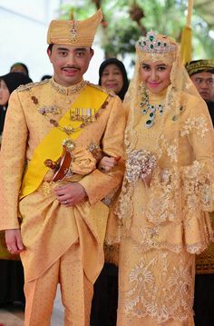 a man and woman dressed in traditional thai garb standing next to each other at a ceremony