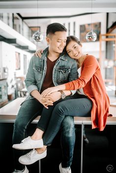 a man and woman sitting on top of a counter next to each other