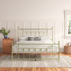 a bedroom with white walls and wood flooring has a metal bed frame in the middle