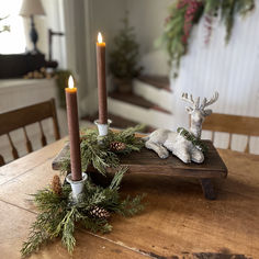 a wooden table topped with two candles and a deer figurine