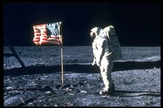 an astronaut standing on the moon next to a flag