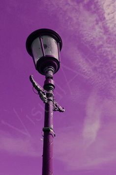 a purple street light with clouds in the background