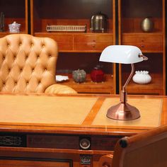 a desk lamp sitting on top of a wooden table next to a chair and bookshelf