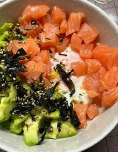 a white bowl filled with salmon and cucumbers