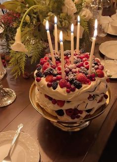 a cake with berries and candles sitting on a table