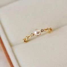 a pearl and diamond ring sitting on top of a white box with gold trimming