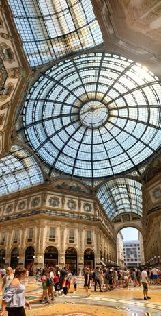 many people are walking around in an ornate building with glass roof and domeed ceiling