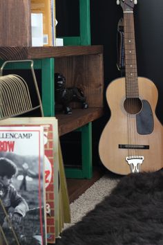 a guitar sitting on the floor next to books