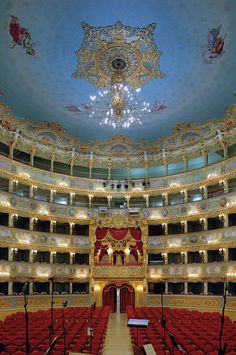 an empty auditorium with red seats and chandelier