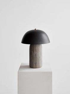 a black and white lamp sitting on top of a table next to a white wall