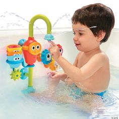 a young boy plays with toys in the water while sitting in a bathtub filled with water