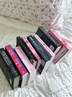 a stack of books sitting on top of a bed next to a white comforter