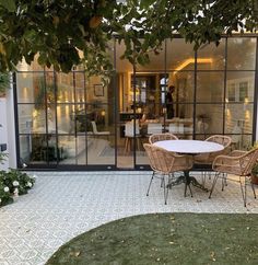 an outdoor patio with table, chairs and potted plants in front of the house