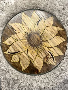 a wooden sunflower painted on the side of a round wall plaque with white fur around it