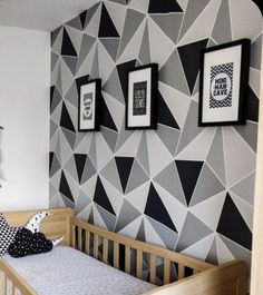 a baby's room decorated in black and white with geometric wallpaper, framed pictures on the wall