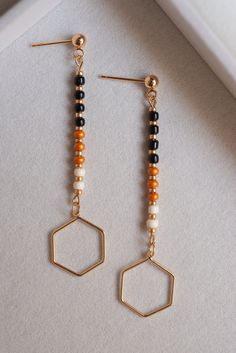 These modern/boho inspired earrings will look great on anyone! They are made with black, cream, and pumpkin colored seed beads. The natural colors reflect fall weather and the light weight make them perfect to wear all day long. The ball post is 4mm and the hexagon charm is 18K gold-plated. Czech glass seed beads are not all identical in shape, so your earrings will not be the exact ones as pictured.  Care Instructions: To keep your earrings looking their best, store them in a dry place away from moisture. Please remove all jewelry before swimming or showering.  These super cool earrings would make a great gift for someone special or just to treat yourself! Please visit my shop for other great listings! https://www.etsy.com/shop/KatlynsJewelryBox Message me with any questions and thank you Popular Earrings, Gold Bead Earrings, Earring Trends, Handmade Earrings Beaded, Handmade Jewelry Diy, Earrings Minimalist, Jewelry Boho, Beaded Dangle Earrings, Small Earrings