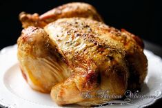 a roasted chicken on a white plate with the words the kitchen whisperer written below