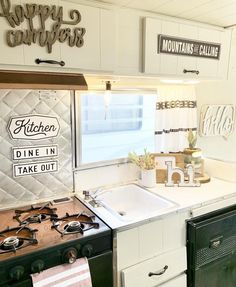 a kitchen with an oven, sink and stove top in front of a sign that says happy campers