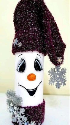 a snowman canister is decorated with purple yarn and silver tinsel, which has an orange nose