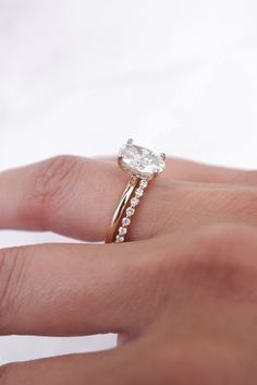 a woman's hand with a diamond ring on top of her finger and an engagement band