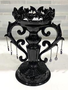 an ornate black vase with chains hanging from it's sides on a white surface