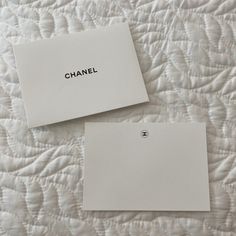 two pieces of paper with the word chanel written on them sitting on a bed