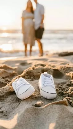 a pair of white shoes sitting on top of a sandy beach