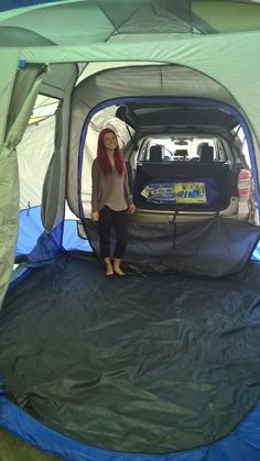 a woman standing next to a car in a tent