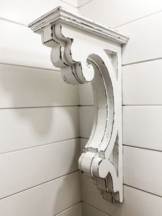 the corner of a white painted wooden wall with an ornate bracket on it's side