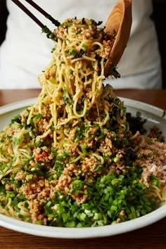 someone is lifting noodles out of a bowl with chopsticks