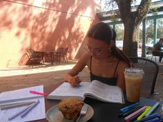 a woman sitting at a table with a book and cup of coffee in front of her